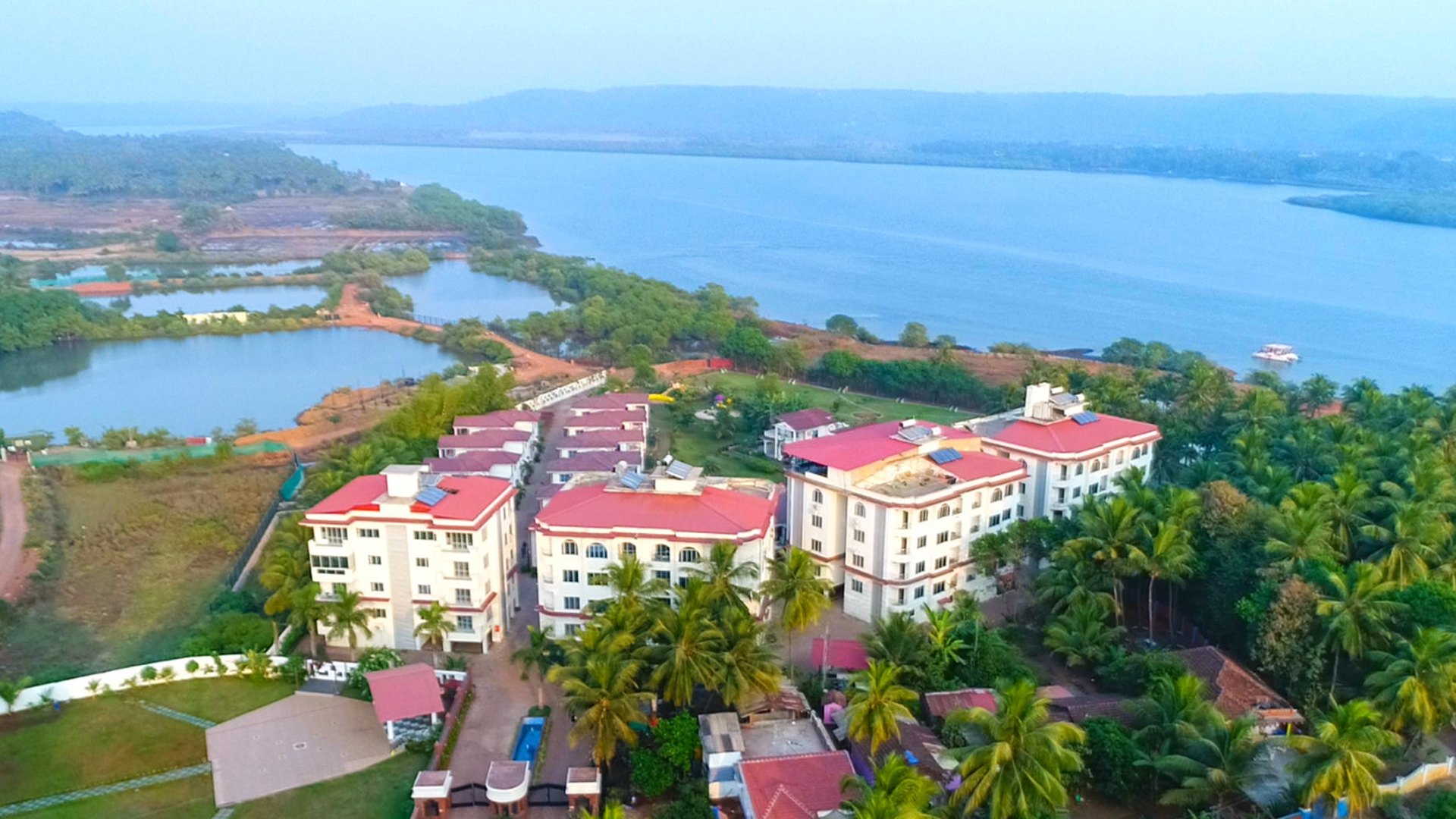 The resort from the air: the suite blocks, villas, the pool and the Chapora estuary beyond